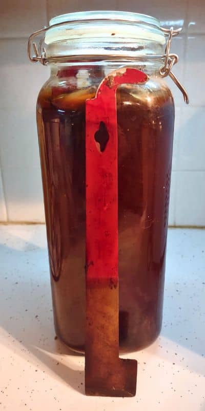 Glass jar with red j-hook hive tools.